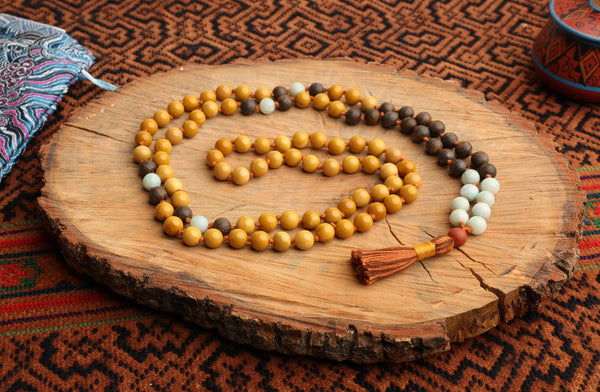 A mala necklace with beads in shades of brown, beige, and blue, and a red tassel, 